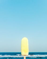 Close-up of ice cream by sea against clear sky