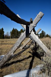 Low angle view of log fence against sky