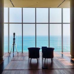 Chairs and sea against sky seen through window