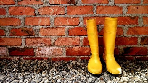 Close-up of yellow shoes on brick wall