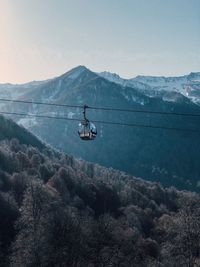 Overhead cable car over mountains against sky