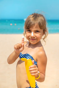 Portrait of smiling girl playing with ball at beach