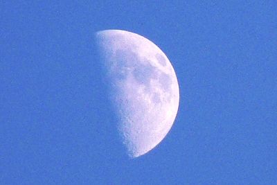 Low angle view of half moon against blue sky