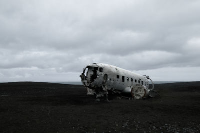 Abandoned airplane on landscape against sky