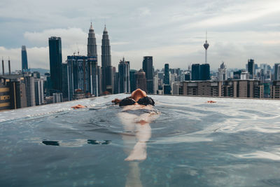 Man on swimming pool against buildings in city