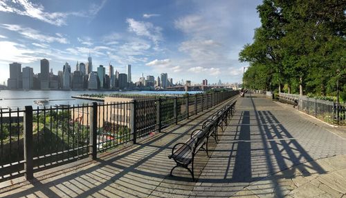 Shadow of benches on footpath with river and financial district in background