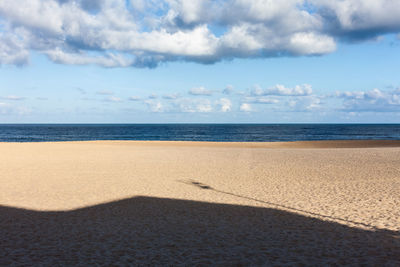 Shadows on the beach against the background of the ocean and cloudy sky