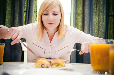 Young woman having food and drink while sitting at home