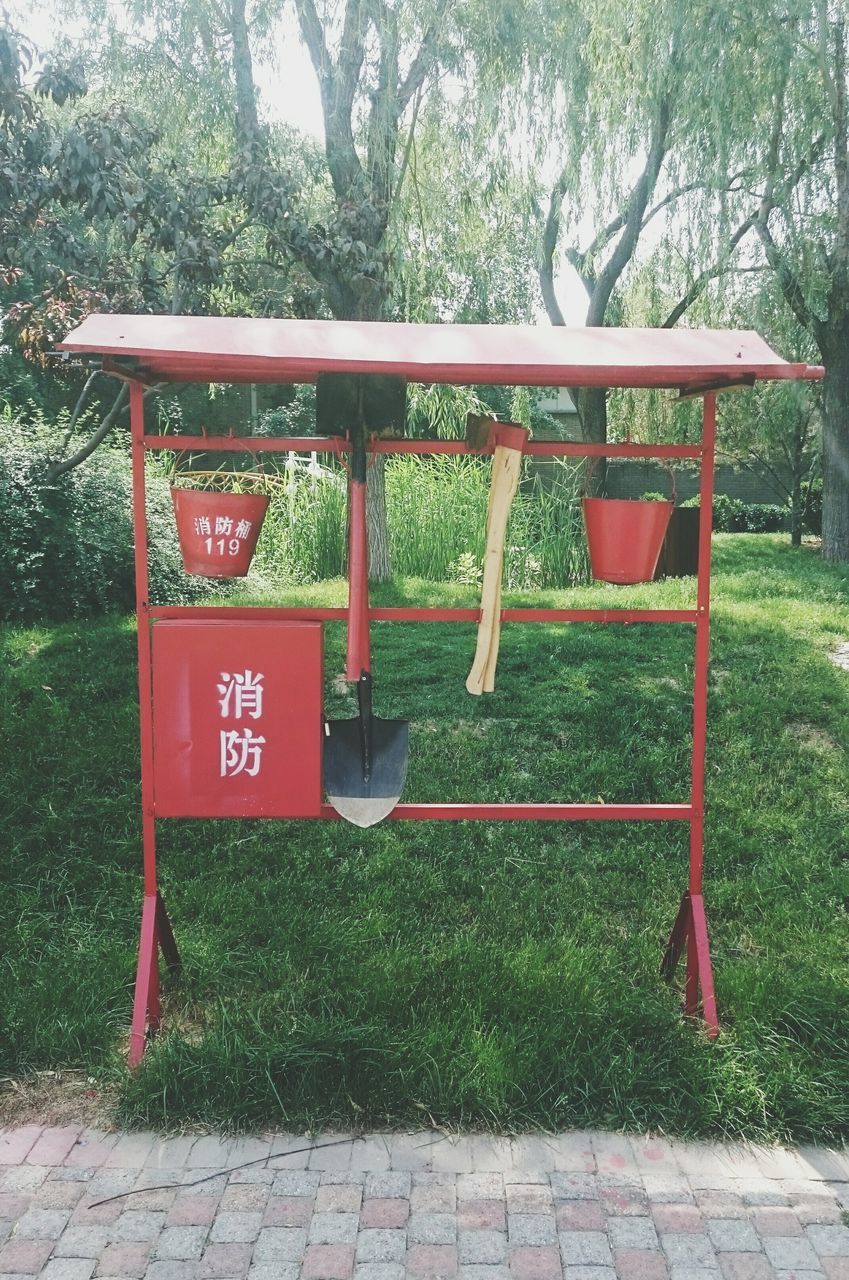 text, communication, tree, western script, red, day, non-western script, plant, grass, bench, growth, outdoors, information sign, park - man made space, sign, no people, absence, information, empty, sunlight