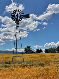 Low angle view of windmill on field against sky