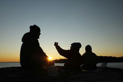 Silhouette of people sitting at sunset