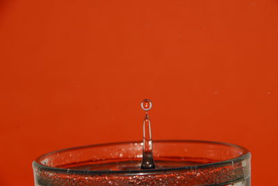 Close-up of water drop over red background