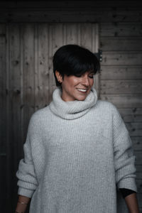 Smiling woman standing against wall in winter
