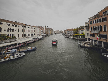 Boats in canal amidst buildings against sky