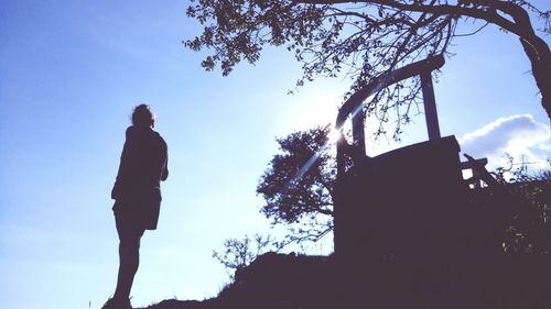 Low angle view of silhouette man standing by tree against sky