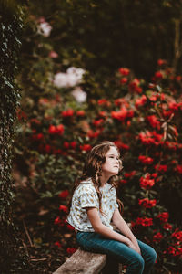 Portrait of young woman standing against plants