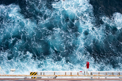 Lifeboat launching appliance from upper view on cruise ship with splashing waves in deep blue sea