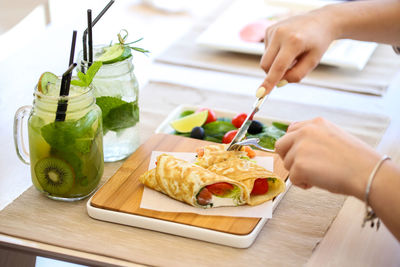 Cropped hands of woman having food and drinks at restaurant