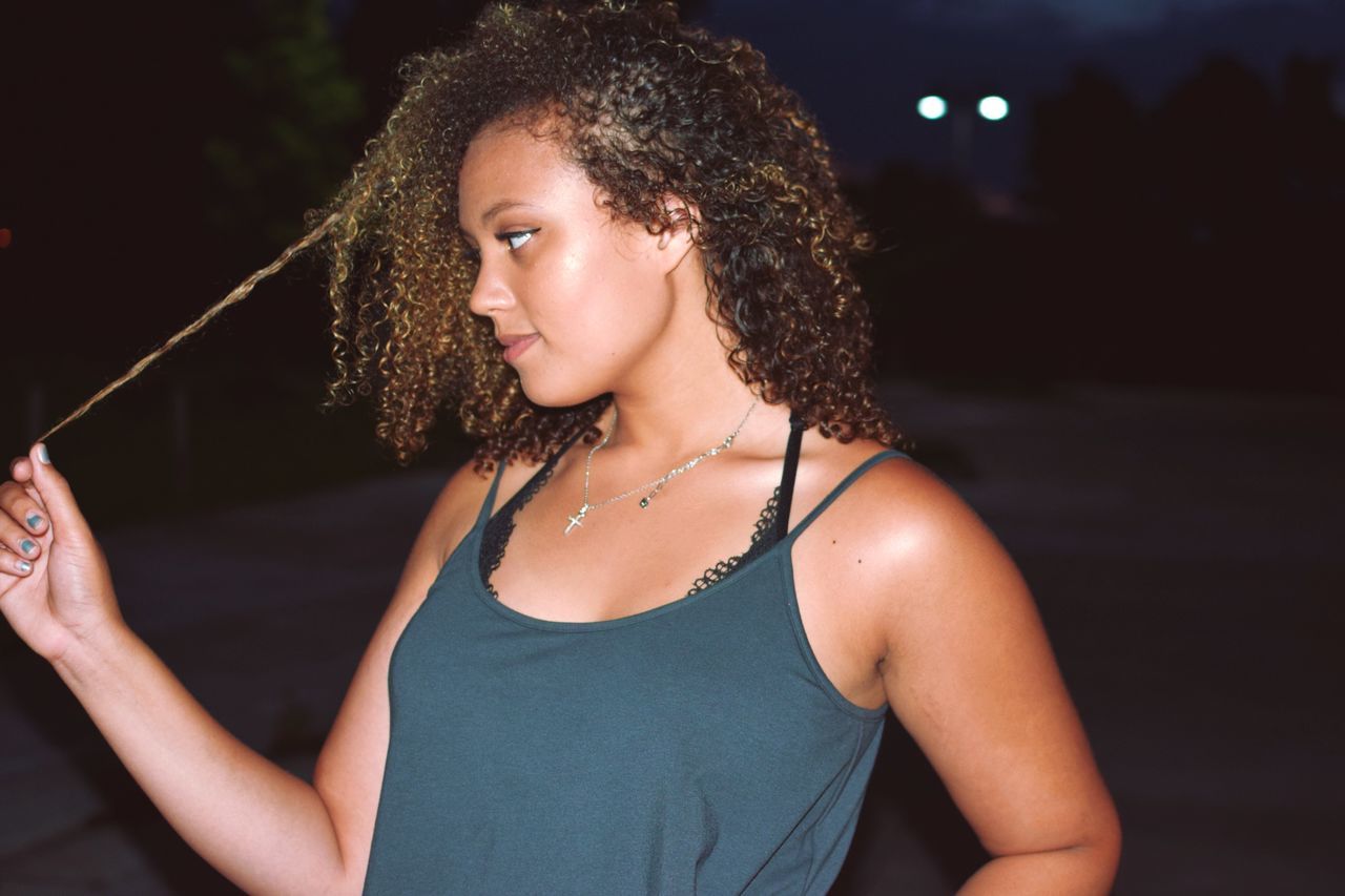 real people, young adult, one person, young women, curly hair, lifestyles, focus on foreground, leisure activity, casual clothing, tank top, night, outdoors, beautiful woman, close-up