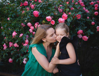 Mother and girl standing by flowering plants