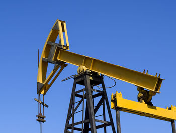 Low angle view of crane against clear blue sky