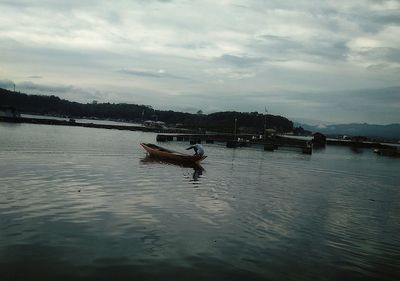 Man in boat on river against sky