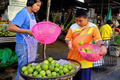 Teenage boy buying oranges from vendor at market stall