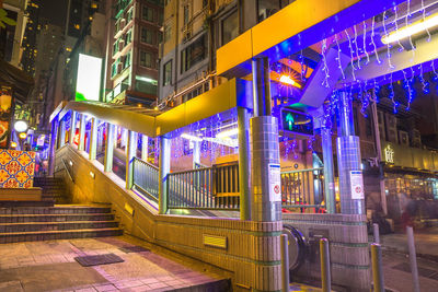 Illuminated street amidst buildings in city at night