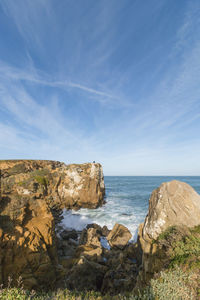 Scenic view of rock formations by sea against sky