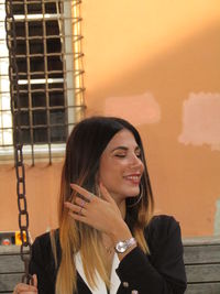 Portrait of smiling young woman standing against built structure