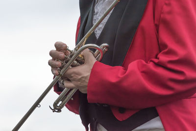 Midsection of male musician holding trumpet against white background