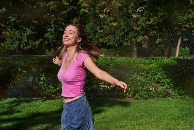 Full length of smiling woman standing against plants