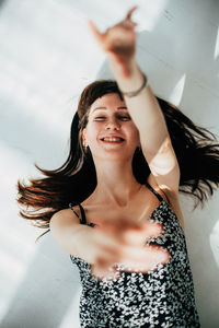 Portrait of smiling young woman gesturing against wall