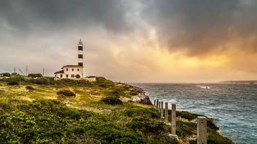 Lighthouse amidst sea and buildings against sky