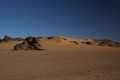 Scenic view of desert against clear blue sky