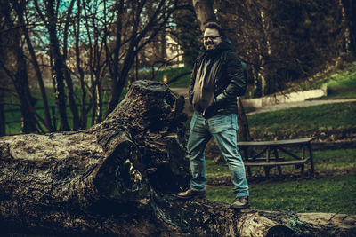 Full length of young man on tree trunk in forest