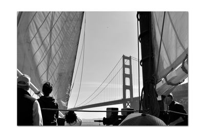 People on bridge in city against sky