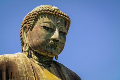 Low angle view of statue against clear blue sky at great buddha statue, kamakura, kanagawa, japan 