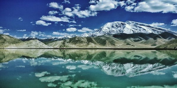 Scenic view of lake by snowcapped mountains against sky