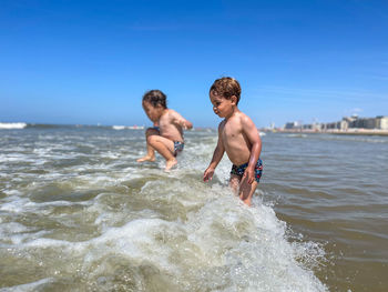 Rear view of shirtless man swimming in sea