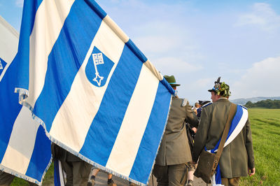 Rear view of people on flags against blue sky