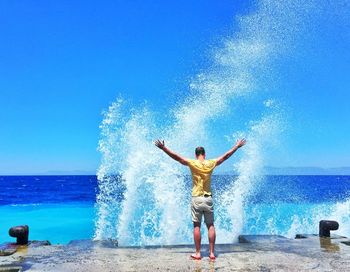 Rear view of woman standing in sea against sky