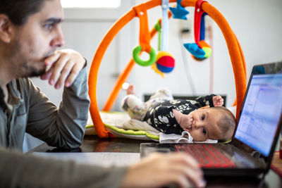 Portrait of girl looking at camera while father working at home