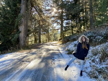 Woman standing on road amidst trees in forest