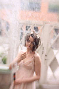 Portrait of woman standing in glass window