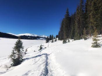 Scenic view of snow covered mountains against clear blue sky