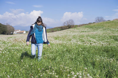 Smiling woman standing on field against sky