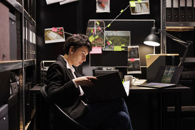 Young woman using laptop while sitting in office