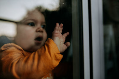 Close-up of cute baby girl seen through glass window