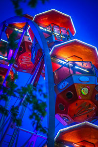 Low angle view of illuminated ferris wheel against blue sky